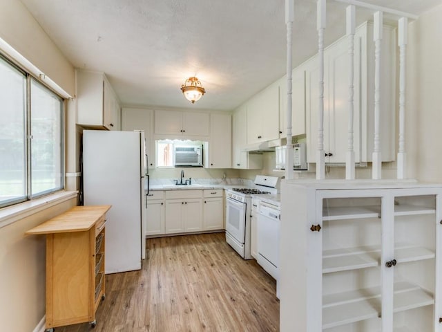 kitchen featuring white cabinetry, a sink, light wood-style floors, light countertops, and white appliances