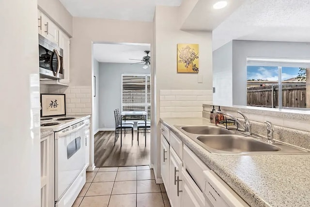 kitchen featuring stainless steel microwave, white cabinets, a sink, electric stove, and a ceiling fan