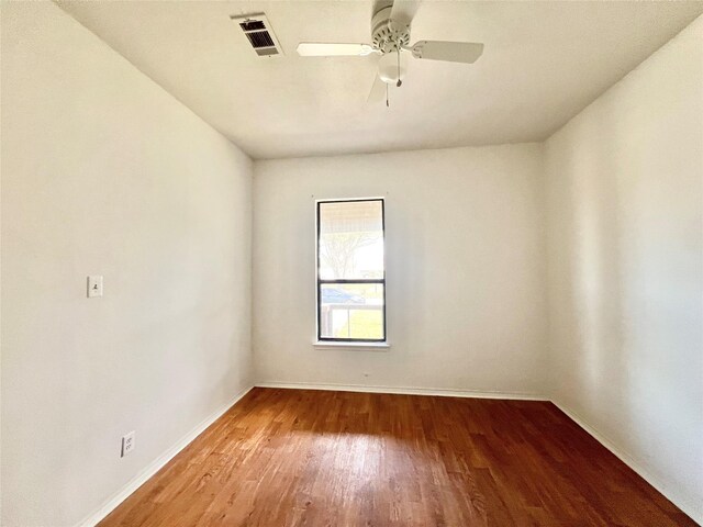 empty room with visible vents, ceiling fan, wood finished floors, and baseboards