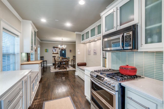 kitchen with stainless steel appliances, backsplash, dark wood-style flooring, and crown molding