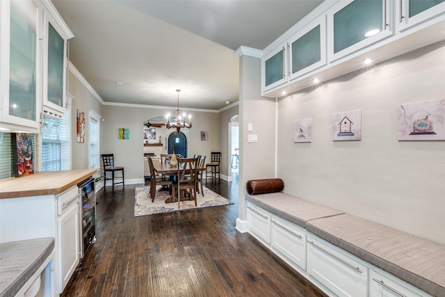 dining room with crown molding, dark wood-style floors, baseboards, arched walkways, and wine cooler