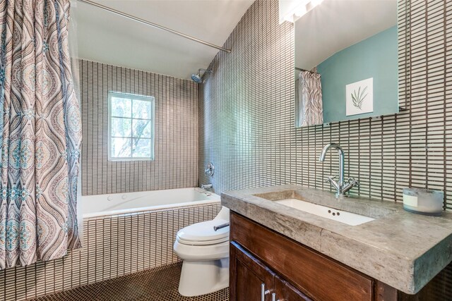 bathroom featuring tiled shower / bath combo, toilet, tile walls, vanity, and tile patterned flooring