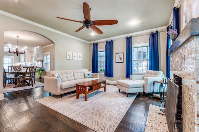 living area with plenty of natural light, arched walkways, wood finished floors, and ceiling fan with notable chandelier