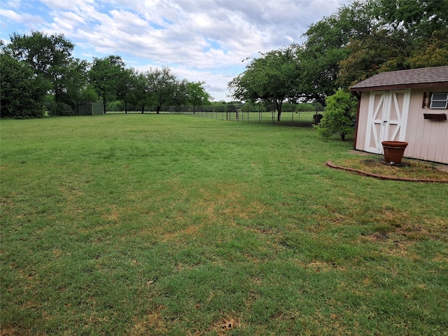 view of yard with fence, an outdoor structure, and a shed