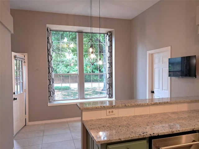 kitchen with light tile patterned floors, light stone countertops, and plenty of natural light