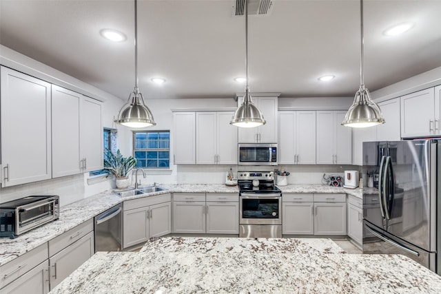 kitchen featuring light stone counters, a toaster, appliances with stainless steel finishes, a sink, and visible vents