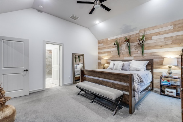 bedroom featuring wood walls, ensuite bathroom, carpet flooring, visible vents, and high vaulted ceiling