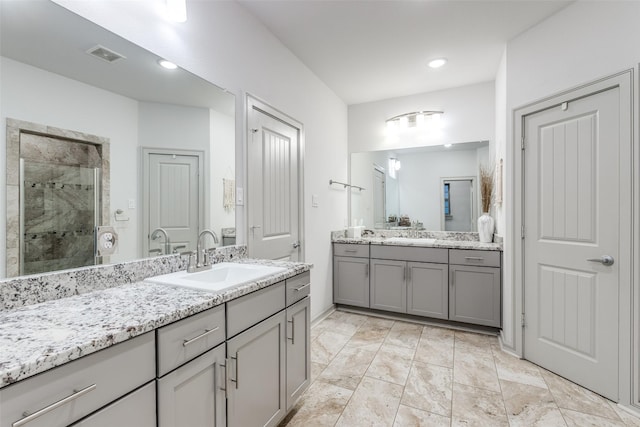 bathroom featuring two vanities, visible vents, a stall shower, and a sink