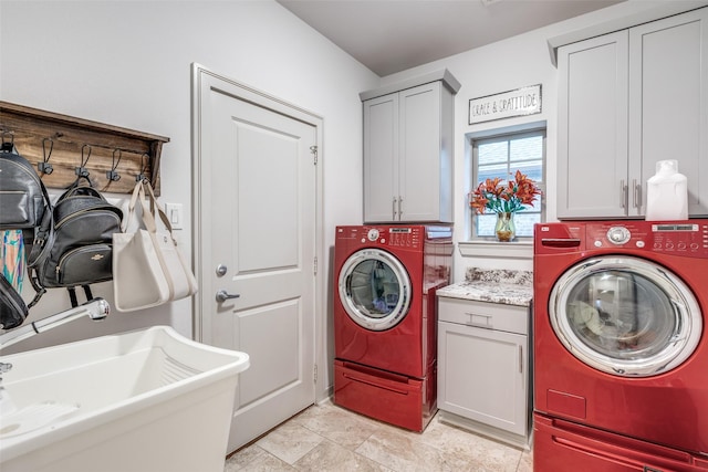 laundry room featuring a sink, cabinet space, independent washer and dryer, and stone finish flooring