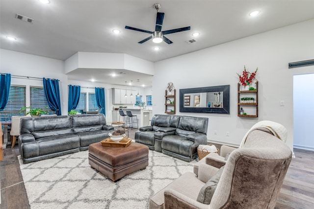 living room featuring baseboards, visible vents, wood finished floors, and a ceiling fan