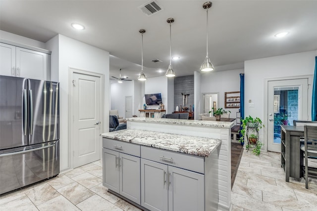 kitchen with visible vents, freestanding refrigerator, gray cabinetry, a center island, and open floor plan