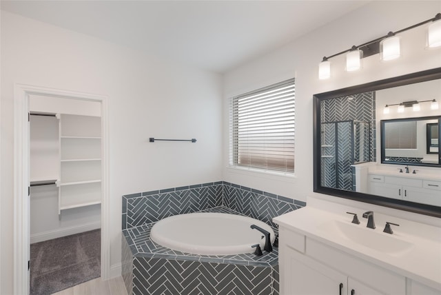full bathroom featuring a sink, a tile shower, two vanities, a walk in closet, and a garden tub