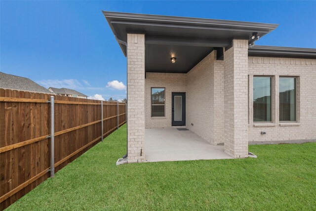 back of house with fence, a lawn, a patio, and brick siding