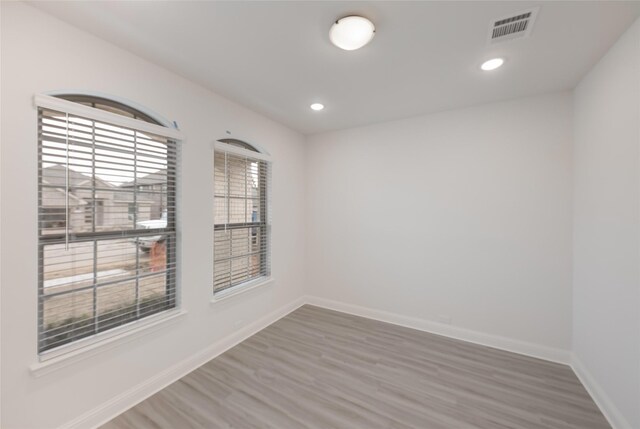 unfurnished room featuring baseboards, visible vents, wood finished floors, and recessed lighting