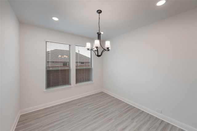 spare room with light wood finished floors, recessed lighting, a chandelier, and baseboards