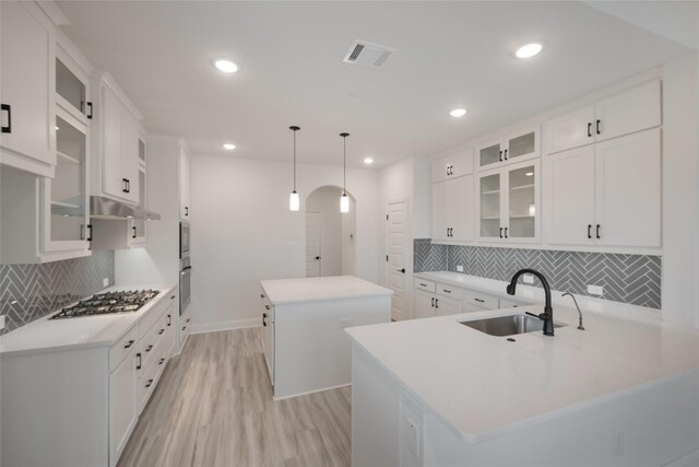 kitchen featuring a sink, visible vents, a kitchen island, light wood-type flooring, and stainless steel gas cooktop