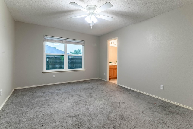 carpeted empty room with a textured ceiling, ceiling fan, and baseboards
