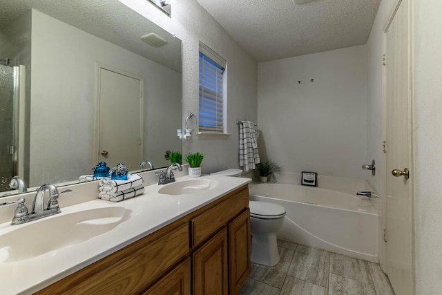 bathroom with toilet, a garden tub, double vanity, and a sink