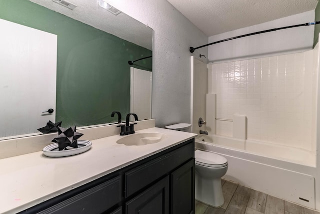 full bath with a textured ceiling, visible vents, toilet, wood finished floors, and vanity