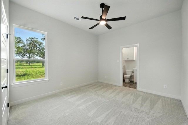 165 Rio Rancho Dr, Decatur, TX 76234 - unfurnished bedroom featuring light colored carpet, multiple windows, connected bathroom, and ceiling fan