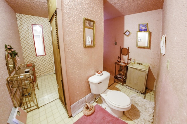 bathroom with a textured ceiling, vanity, and toilet