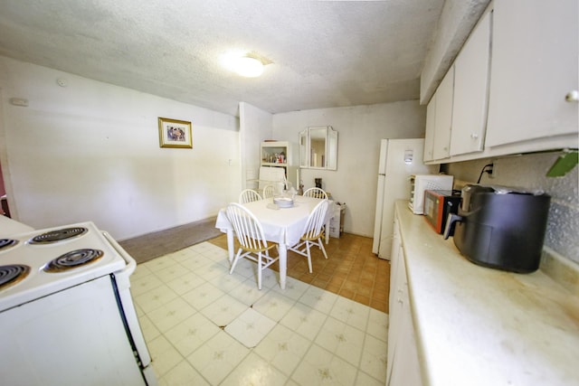 kitchen featuring light countertops, a textured ceiling, white cabinetry, and white appliances