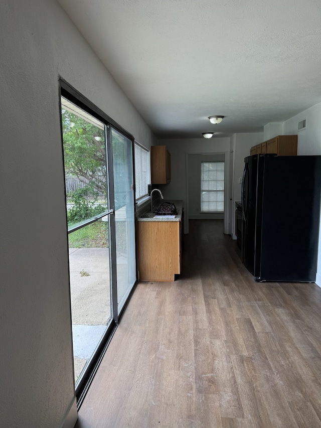 kitchen with visible vents, a healthy amount of sunlight, freestanding refrigerator, and light wood-type flooring