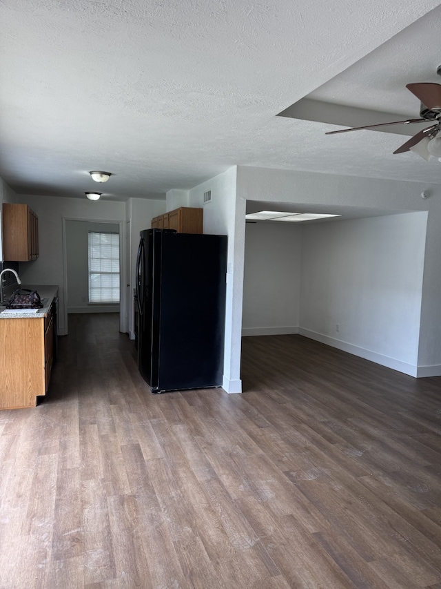 kitchen with baseboards, wood finished floors, a textured ceiling, and freestanding refrigerator