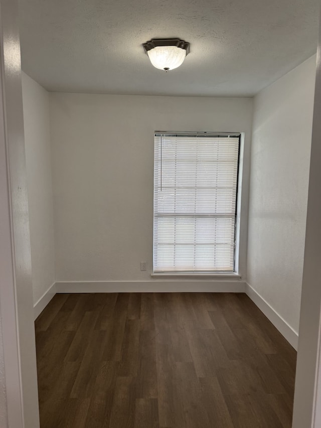 unfurnished room with dark wood finished floors and baseboards