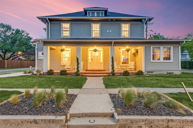 traditional style home featuring fence, a porch, and a front lawn