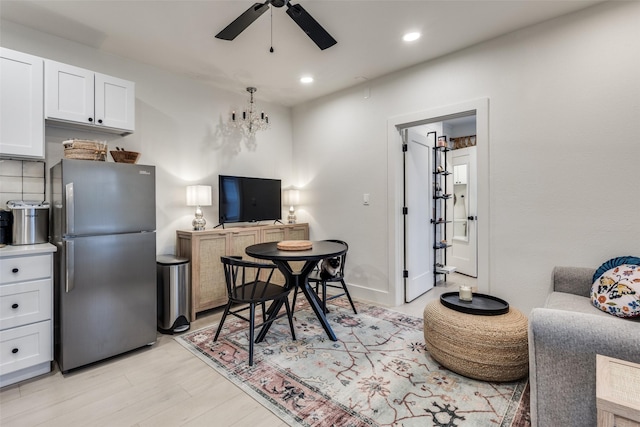 living room featuring recessed lighting, light wood-style floors, and ceiling fan with notable chandelier