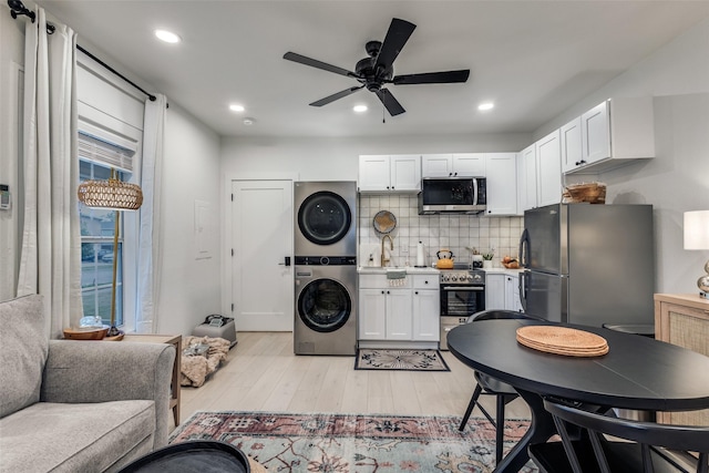 521 Texas St, Denton, TX 76209 - kitchen with stacked washer / drying machine, light wood-type flooring, a sink, stainless steel appliances, and white cabinetry