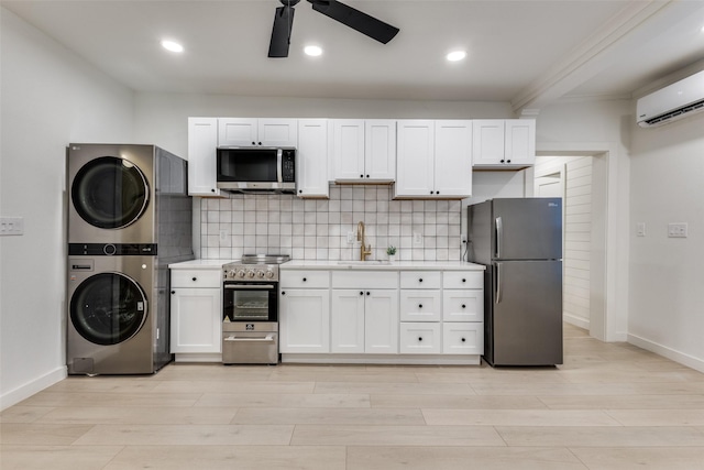kitchen featuring a sink, ceiling fan, stacked washer / drying machine, stainless steel appliances, and light countertops