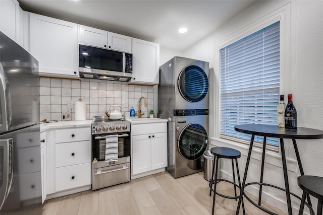 521 Texas St, Denton, TX 76209 - kitchen with appliances with stainless steel finishes, a sink, light countertops, tasteful backsplash, and stacked washer and clothes dryer