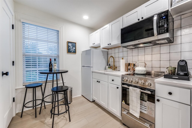 521 Texas St, Denton, TX 76209 - kitchen with white cabinets, a sink, light wood finished floors, stainless steel appliances, and backsplash