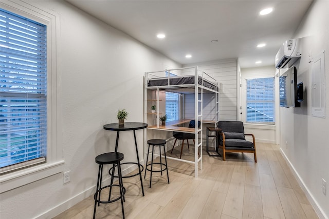 bedroom with baseboards, recessed lighting, a wall unit AC, and wood finished floors