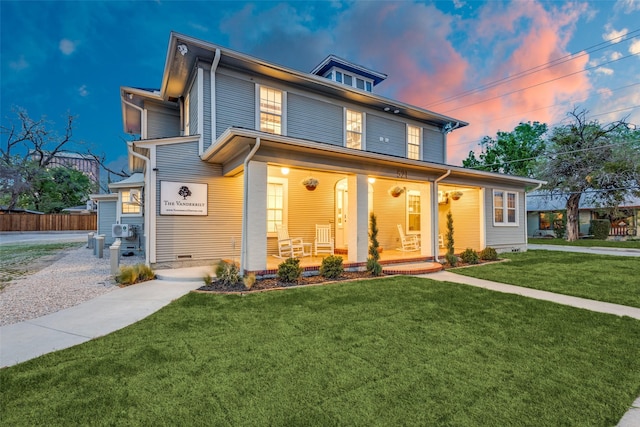 traditional style home with a porch, a lawn, and fence
