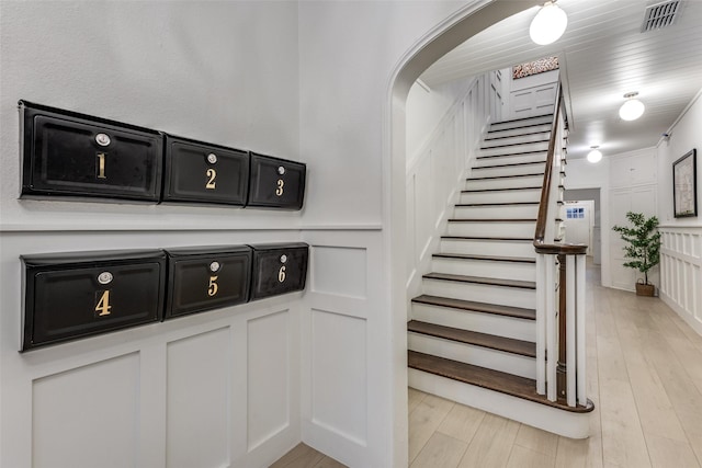 stairway with visible vents, wood finished floors, and a decorative wall
