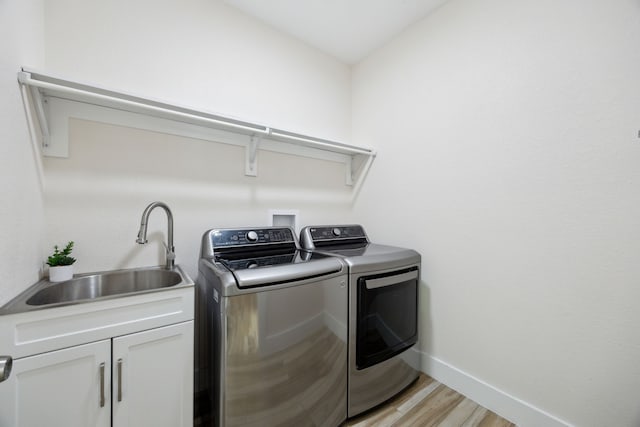 4435 Cicero St, Dallas, TX 75216 - laundry room with cabinet space, a sink, baseboards, light wood-type flooring, and washer and clothes dryer