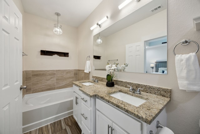 4435 Cicero St, Dallas, TX 75216 - bathroom featuring visible vents, wood finished floors, a garden tub, and a sink