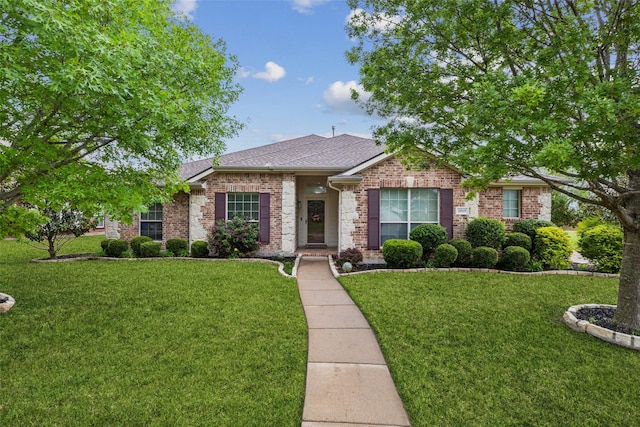 ranch-style home featuring brick siding, roof with shingles, and a front yard