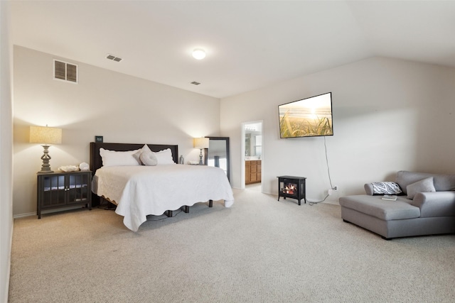 carpeted bedroom with visible vents, vaulted ceiling, and ensuite bath