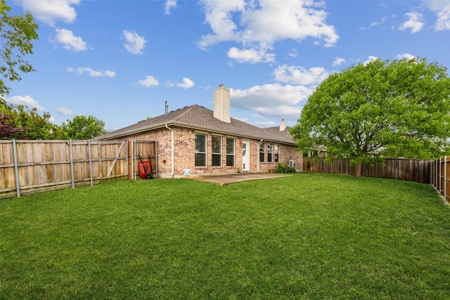 back of property featuring a yard, brick siding, a chimney, and a patio area
