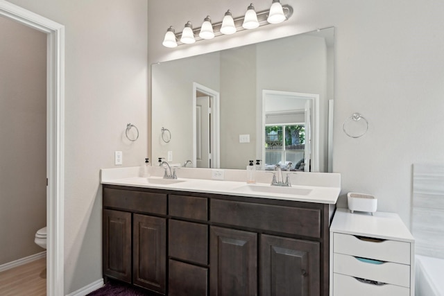full bathroom with toilet, double vanity, a sink, and a washtub