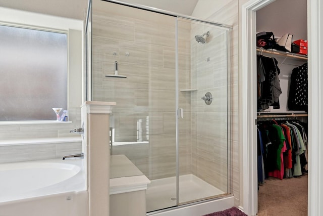 bathroom featuring a spacious closet, a stall shower, and a bath