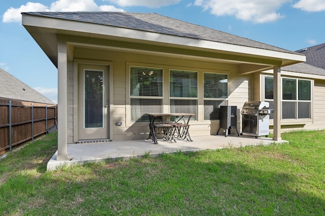 rear view of house with a patio, fence, a yard, and roof with shingles
