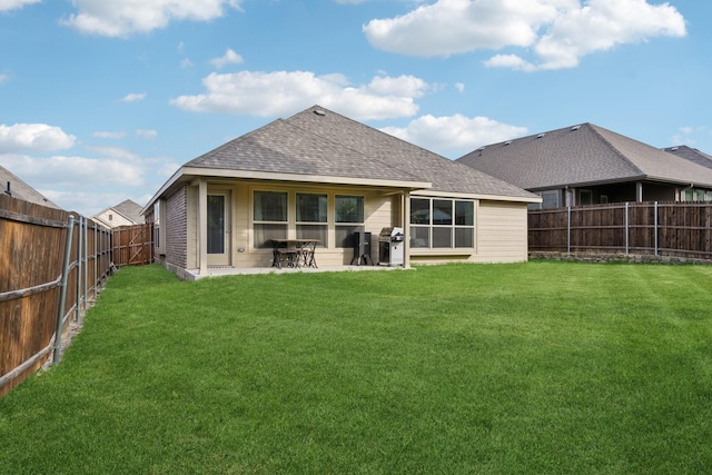 rear view of house featuring a lawn, a patio, a fenced backyard, and roof with shingles