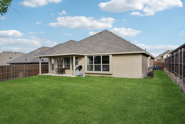 rear view of property featuring a patio area, a shingled roof, a lawn, central AC, and a fenced backyard