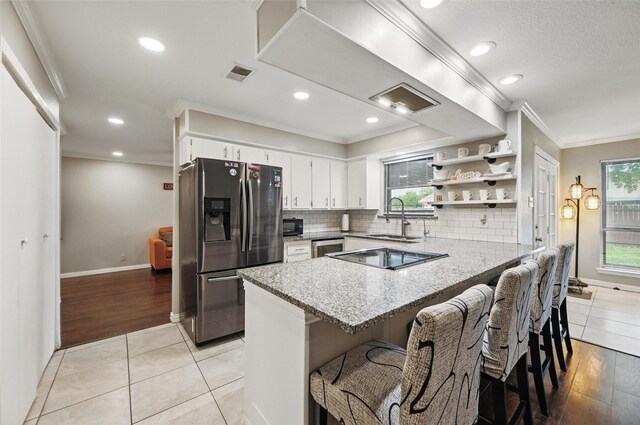 1501 SE 4th St, Grand Prairie, TX 75051 - kitchen with stainless steel fridge with ice dispenser, a peninsula, healthy amount of natural light, crown molding, and white cabinets