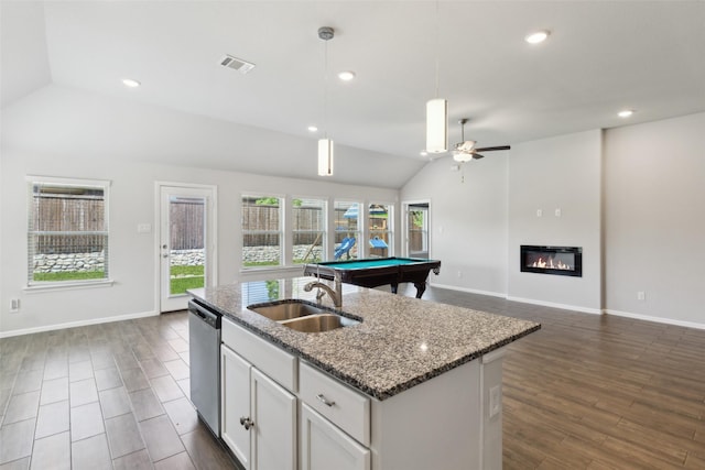 kitchen with stainless steel dishwasher, a sink, ceiling fan, open floor plan, and vaulted ceiling